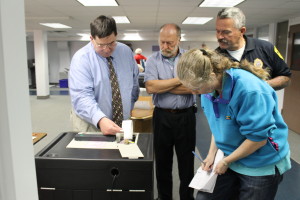 Falmouth Town Clerk Michael Palmer gets his first look at election results for Precinct 1 Tuesday night while Precinct Warden Greg Ketterer and Falmouth Police Detective Robert Murray look on and Catherine Bumpus writes down the results.