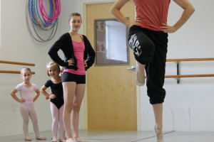 Tiny dance students peek around assistant dance teacher Annie Lawrence to watch dance teacher Cara McManus demonstrate a skip at Turning Pointe Dance Studio.
