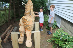 Children seem fascinated by a carousel horse in the process of being made. Wood blocks of Eastern white pine are laminated together, then the artist uses a chainsaw and then a chisel before dying and painting the horse.