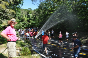 Roger Day sprays the Falmouth Road Race runners from his Nobska Road property, an annual tradition.