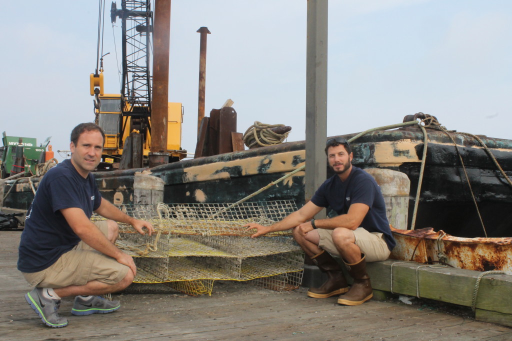 Peter Chase and Eric Matzen, who farm oysters in Buzzards Bay, pose next to oyster farming gear on the Woods Hole dock.