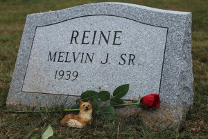 A small ceramic fox is among the flowers placed at the grave site of Melvin Reine Sr., who died this week at the age of 74.