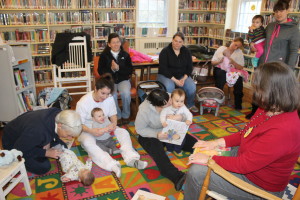 Mothers and their children along with volunteers from Angel House in Hyannis listen to a presentation by Cotuit Library Youth Services Director Lenore Levine, at right.