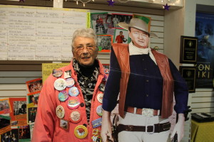 Letti Sullivan, one of the founders of First Night Chatham, poses with John Wayne, one of the cardboard cut-outs displayed during the Noise Parade as a tribute to the new Chatham Orpheum Theater, the new cinema that opened this year on Main Street thanks to an outpouring of community support. Sullivan wears buttons from all 23 years of the First Night Chatham event.