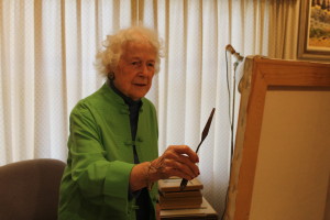 The artist Marguerite Falconer faces her canvas with a palette knife.