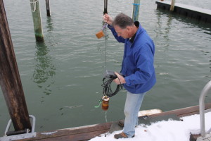 Doc Taylor pulls a canister out of Falmouth Inner Harbor, taking surface water to test as part of the Pond Watch program.