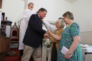 Paul Rifkin's sponsors lay their hands on him at the altar, as the Rev. Fields gives a blessing.