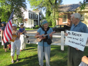 Paula Pace, with the ukelele, demonstrating in favor of allowing immigrant children at Camp Edwards