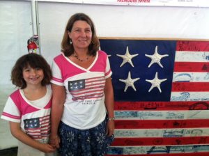 Artist Karen Scata poses with her daughter, Siena Bos, 10, in front of the American flag she designed using the artwork of children from Bourne, Sandwich and Wareham.