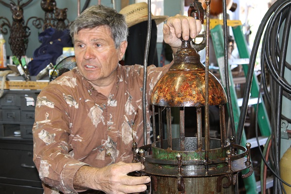 Michael Kacergis with a metal lighthouse he made at his welding shop in Provincetown.