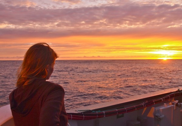 Julie Huber chief scientist of an expedition, watches the sunrise in the northeast Pacific. PHOTO CREDIT: CAROLA BUCHNER